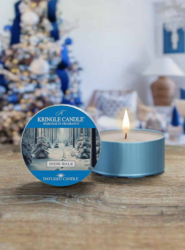 Kringle Candle daylight candle with blue packaging on a wooden surface, Christmas tree in the background