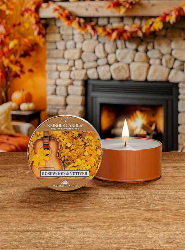 Lit DayLight candle in "Rosewood & Vetiver" scent. Label shows a guitar and autumn leaves.