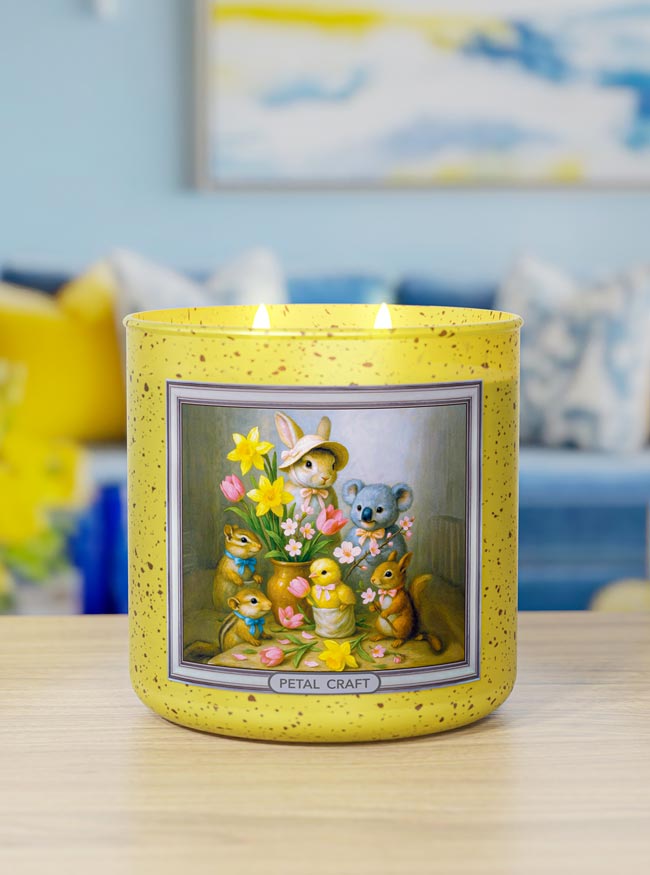 Yellow candle with a decorative label featuring cartoon characters on a table.
