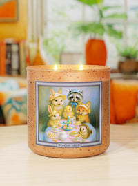 Candle with a decorative label featuring cartoon characters on a table.