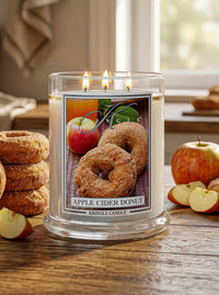 Kringle Candle Apple Cider Donut candle with apples and donuts on a wooden surface