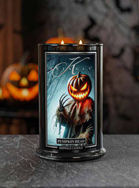 Kringle Candle with 'Pumpkin Head' design on a dark surface with pumpkins in the background