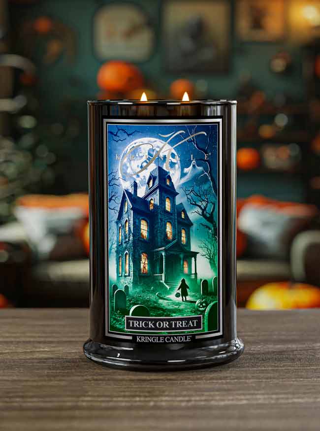 Kringle Candle Halloween-themed candle with a haunted house design on a wooden surface.
