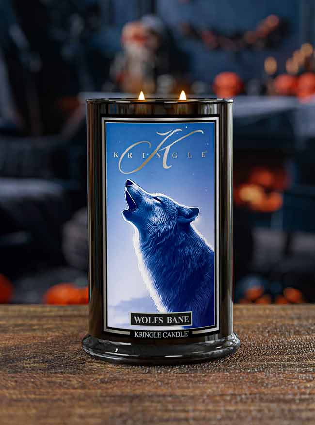 Lit Halloween candle  on wood base labeled "Wolf's Bane" with an image of a howling wolf under a blue sky.