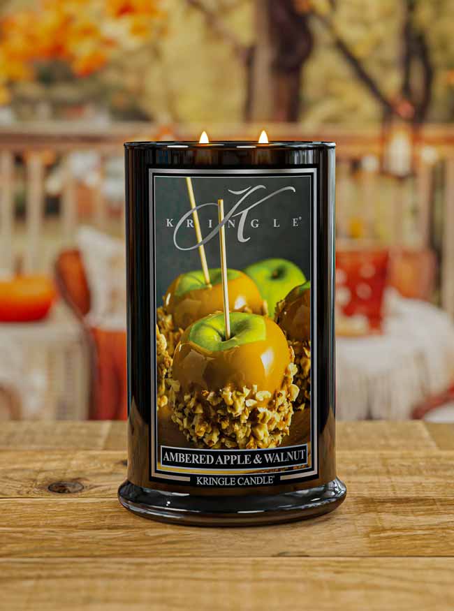 Kringle Candle with 'Ambered Apple & Walnut' fragrance on a wooden surface.
