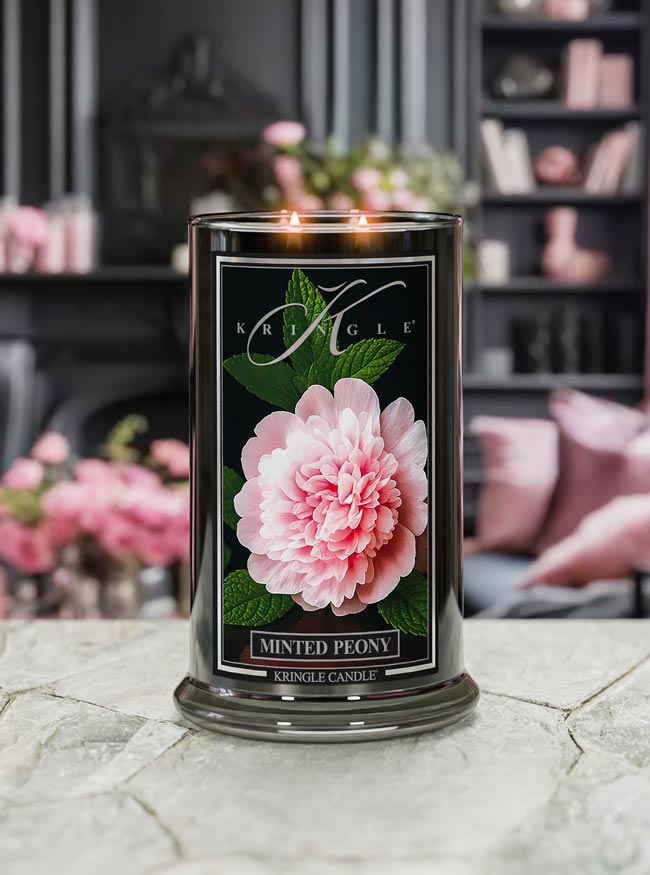 Kringle Candle Minted Peony 2-wick lit candle with pink flower design on a marble surface
