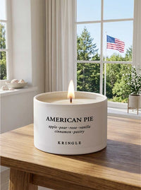American Pie mini tin by Kringle Candle on a table near a window with American flag outdoors