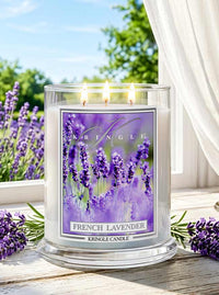 Kringle Candle French Lavender candle on a wooden surface with lavender flowers in the background.