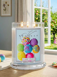 Kringle Candle with colorful cake pop design on a table with a window view.