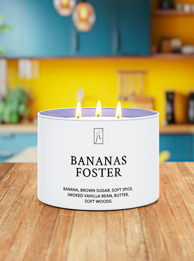 Candle labeled 'Bananas Foster' on a wooden surface with a blurred kitchen background