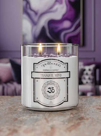 Lit Tranquil Mind Scented candle with a label on a surface, with a blurred background