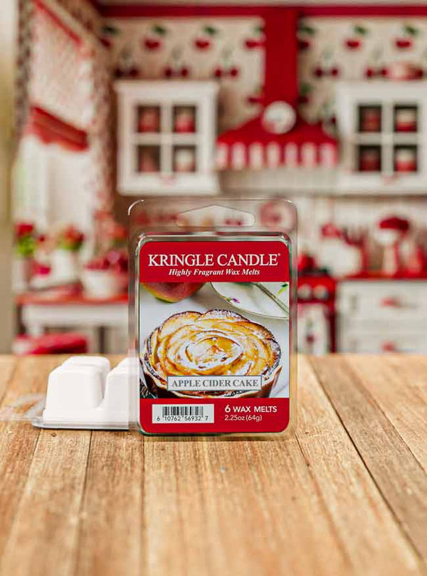 Kringle Candle Apple Cider Cake wax melt packaging on a wooden surface with a blurred kitchen background.