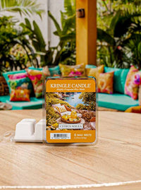 Kringle Candle Citrus Solea wax melt package on a wooden surface with a colorful outdoor setting in the background