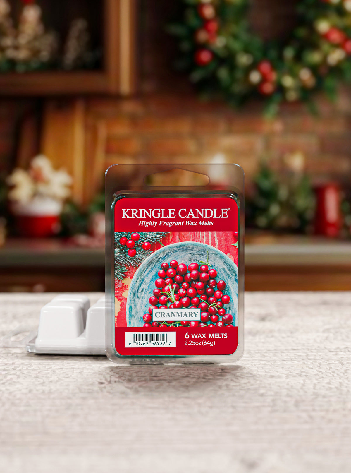 A package of Kringle Candle Granmary highly fragrant wax melts stands on a light textured surface with its white plastic clamshell tray partially visible behind it. The product packaging features a red label with an illustration of red cranberries in a blue bowl.