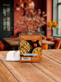 Kringle Candle Apple Pumpkin Pie wax melt package on a wooden table with a blurred indoor background.