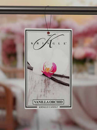 Kringle Candle Vanilla Orchid air freshener with a pink orchid on a blurred background.