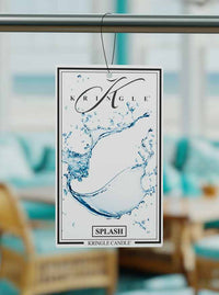 Kringle Candle Splash air freshener hanging in a room with blurred furniture and decor.