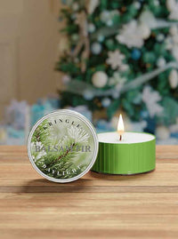 Green candle with 'Kringles' branding in front of a decorated Christmas tree.