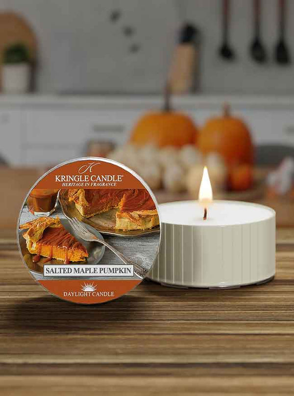 Kringle Candle salted maple pumpkin candle on a wooden surface with pumpkins in the background