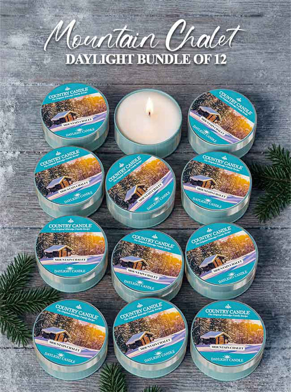 Set of 12 Country Candle Mountain Chalet Daylight candles on a wooden surface with evergreen branches.