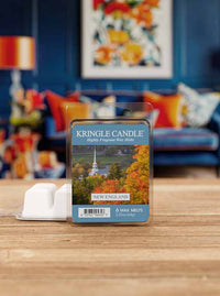 Kringle Candle wax melts packaging on a wooden surface with a colorful abstract painting in the background.