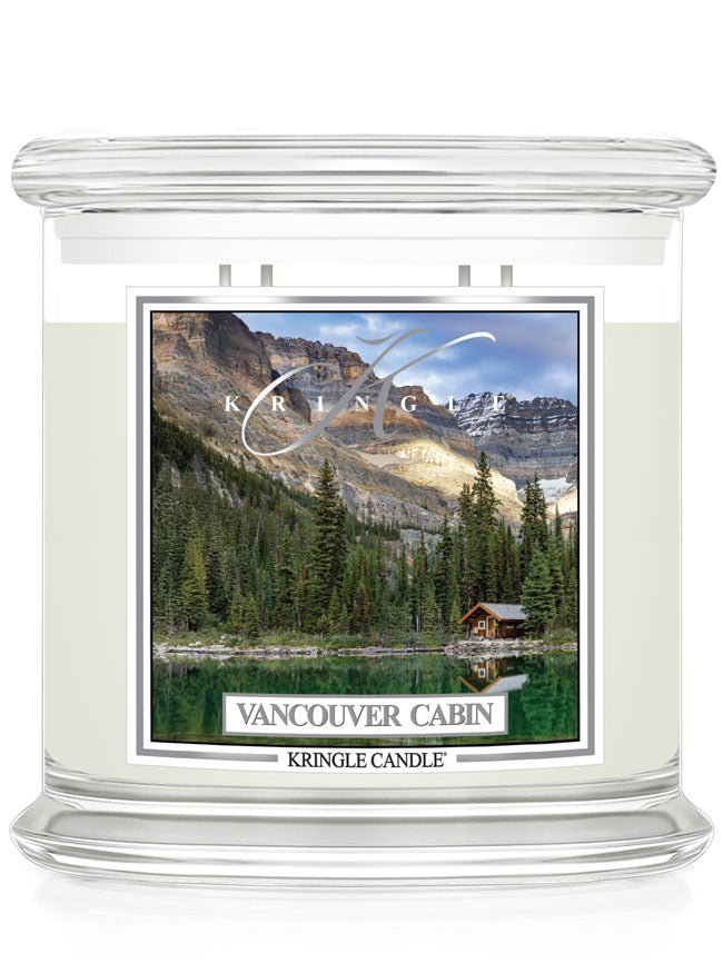 Unlit XL 4-Wick candle with a label showing a cabin by a forest and lake, under mountain peaks.