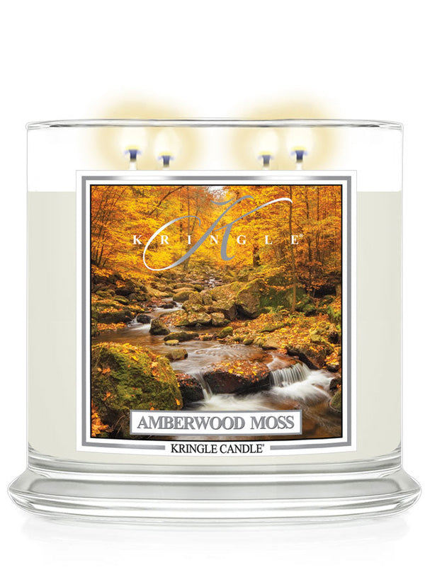 Lit XL 4-wick candle, Amberwood Moss. Label features an autumn forest with a flowing stream among mossy rocks.