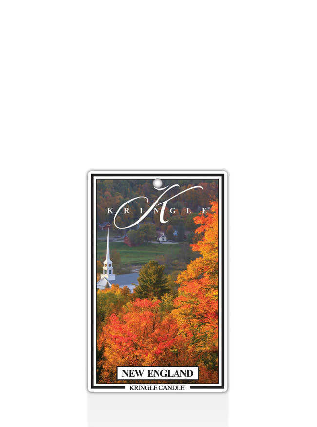 Kringle Candle New England air freshener with a scenic design of trees and a church in the background.