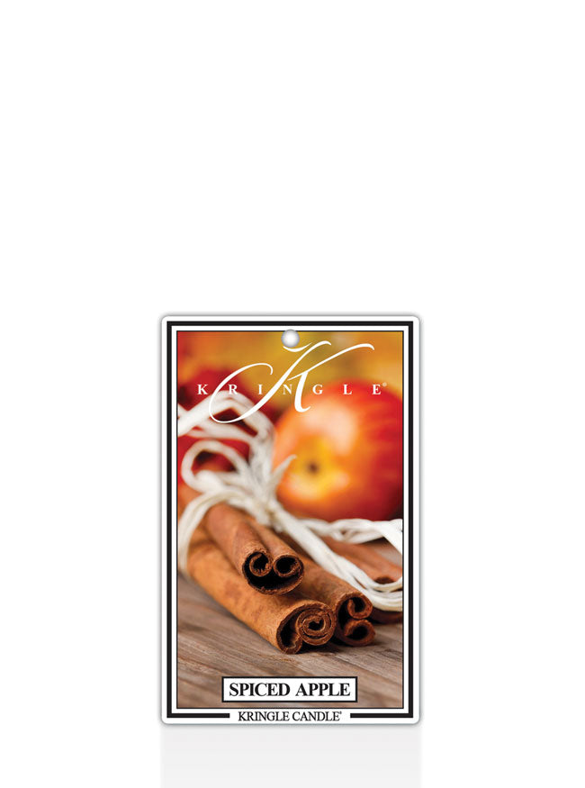 Kringle Candle Spiced Apple air freshener with apples, cinnamon sticks, and white ribbon on a white background.