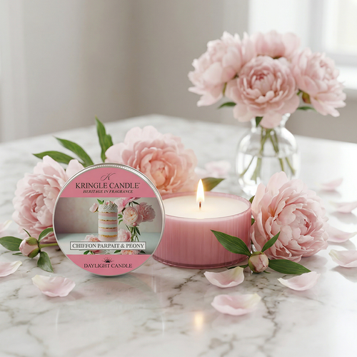 Pink candle with floral design on a marble surface, surrounded by pink flowers.