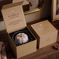 An open kraft gift box reveals a pale lavender pumpkin-shaped candle with a gold top, next to a closed matching box. The inside lid reads 'THE PUMPKIN COLLECTION KINGSLAND CANDLE CO.