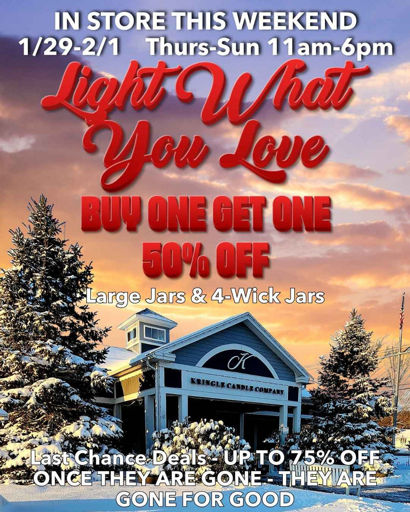 Snow-covered exterior of the Kringle Candle flagship store at sunset with promotional text announcing an in-store weekend event, Buy One Get One 50% Off on large jars and 4-wick jars, and last chance deals up to 75% off.