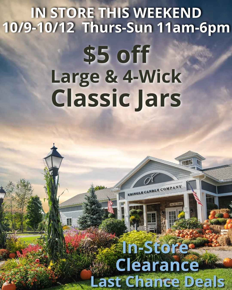 A scenic view of the Kringle Candle store in Bernardston, Massachusetts, surrounded by colorful fall flowers and pumpkins under a cloudy autumn sky. Text on the image announces an in-store promotion: "$5 off Large & 4-Wick Classic Jars" and highlights "In-Store Clearance Last Chance Deals," with the event running Thursday through Sunday, October 9–12, from 11 AM to 6 PM.
