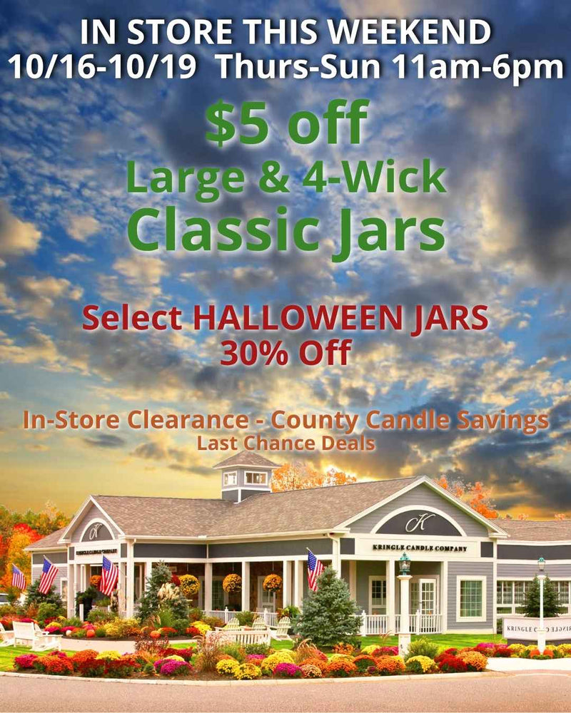 Exterior of the Kringle Candle Company store in Bernardston, MA, surrounded by colorful fall mums and American flags. Promotional text reads: “In Store This Weekend 10/16–10/19 Thurs–Sun 11am–6pm. $5 off Large & 4-Wick Classic Jars. Select Halloween Jars 30% Off. In-Store Clearance – County Candle Savings – Last Chance Deals.”