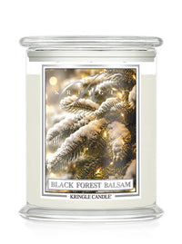 A Kringle Candle jar candle labeled 'Black Forest Balsam' with a frosted glass container, clear lid, and a front label showing snowy pine branches with warm lights.