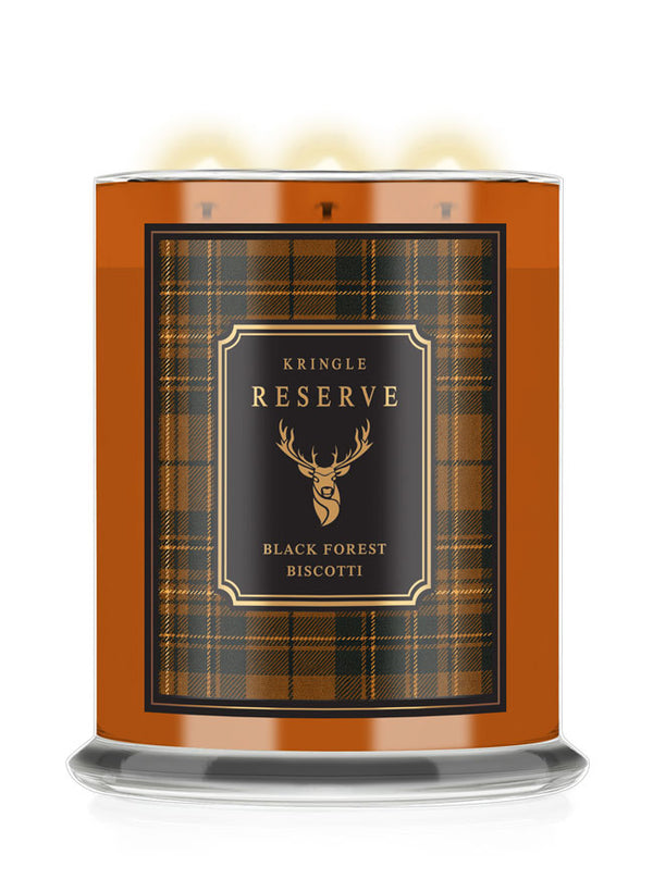 A three-wick scented candle in a cylindrical glass jar with a warm orange-brown body, featuring a black and gold plaid label that reads 'Kringle Reserve' and 'Black Forest Biscotti' with a deer head logo. The candle is shown lit with three glowing flames against a clean white background.