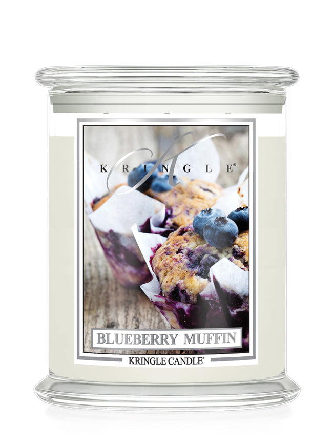 A Kringle Candle jar candle with a clear glass container and a cream-colored wax body. The front label features a photograph of blueberry muffins and reads 'BLUEBERRY MUFFIN' with the brand name 'KRINGLE' at the top.