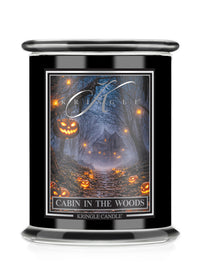 A black glass jar candle with a clear lid, featuring a Halloween-themed label that reads 'Cabin in the Woods' and shows a haunted forest scene with glowing jack-o'-lanterns. The brand name 'Kringle Candle' is visible on the label.