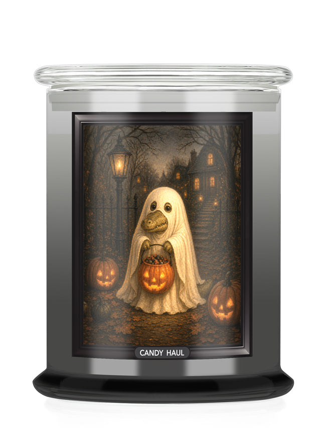 A jar candle with a Halloween-themed printed label showing a ghost alligator holding a jack-o'-lantern in a haunted house scene. The candle has a clear glass lid and a black base, with the brand name 'CANDY HAUL' printed at the bottom of the label.