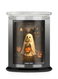 A jar candle with a Halloween-themed printed label showing a ghost alligator holding a jack-o'-lantern in a haunted house scene. The candle has a clear glass lid and a black base, with the brand name 'CANDY HAUL' printed at the bottom of the label.