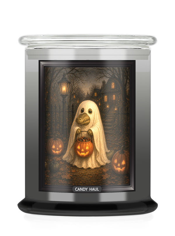 A jar candle with a Halloween-themed printed label showing a ghost alligator holding a jack-o'-lantern in a haunted house scene. The candle has a clear glass lid and a black base, with the brand name 'CANDY HAUL' printed at the bottom of the label.