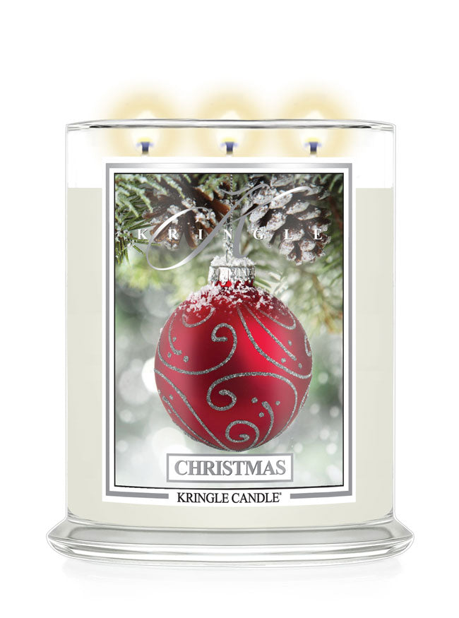 A Kringle Candle 'Christmas' scented candle in a clear glass jar with three lit wicks, featuring a front label with a red ornament and pinecone design on a white background.