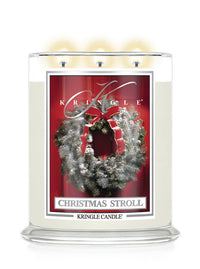 Christmas Stroll scented lit 3-wick candle by Kringle Candle with a red label and a holiday wreath on a door.