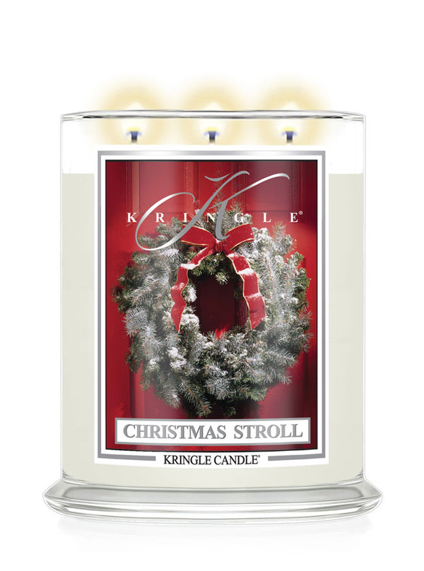 Christmas Stroll scented lit 3-wick candle by Kringle Candle with a red label and a holiday wreath on a door.