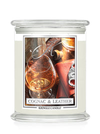 A Kringle Candle jar candle labeled 'Cognac & Leather' with a clear glass jar, white wax, and a front label showing a cognac glass, leather, and metal hardware on a white background.