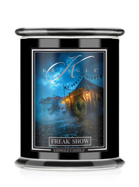 A black glass jar candle featuring a front label for Kringle Candle Halloween scent 'Freak Show' with an illustration of a circus tent at night.