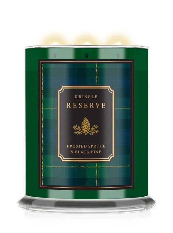 A Kringle Reserve candle in a cylindrical green tin with a black and gold label reading 'Frosted Spruce & Black Pine,' shown on a white background with warm light glowing from the top wicks.