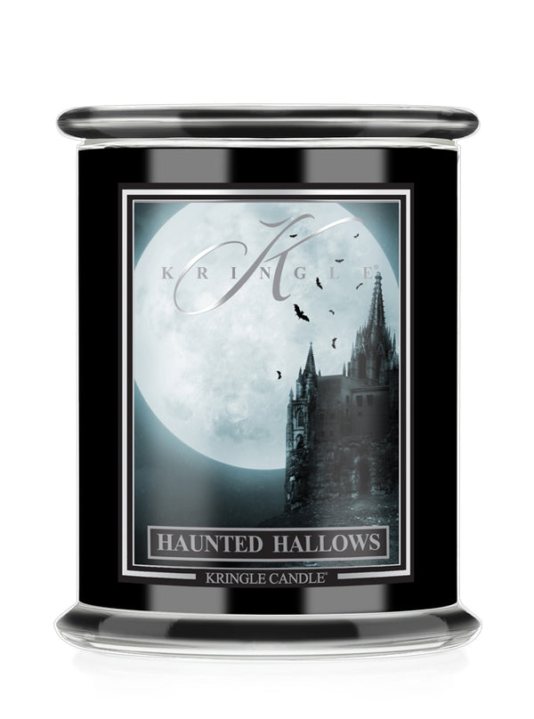 A black glass jar candle with a silver metal lid and a front label depicting a gothic castle silhouette against a large full moon, with the text 'KRINGLE CANDLE' and 'HAUNTED HALLOWS'.