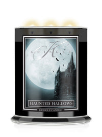 A Kringle Candle jar labeled 'Haunted Hallows' with a black container, a gothic-style label showing a moonlit castle and full moon, and three glowing candles visible at the top on a white background.