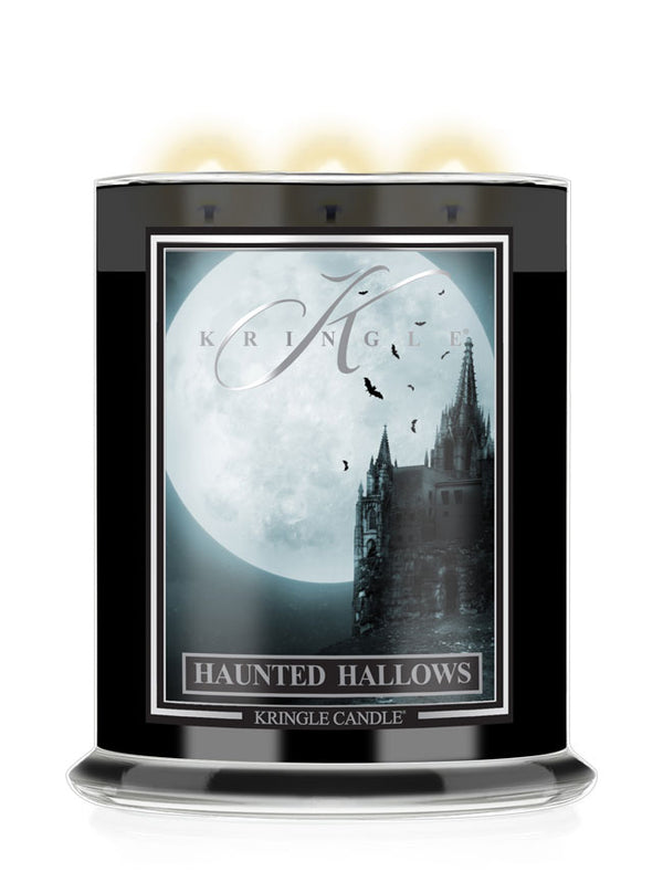A Kringle Candle jar labeled 'Haunted Hallows' with a black container, a gothic-style label showing a moonlit castle and full moon, and three glowing candles visible at the top on a white background.